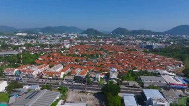 Tayland, Phuket Adası 'nın havadan görünüşü, kırmızı çatılı evler, yemyeşil yemyeşil, küçük bir göl, yuvarlanan tepeler ve tropikal bir şehir manzarası..