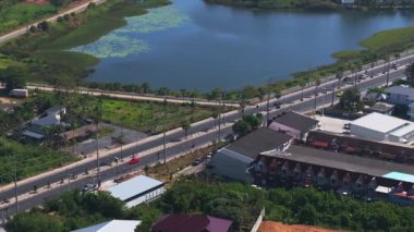 Tayland, Phuket 'te bir yerleşim bölgesinin havadan görüntüsü, kırmızı ve gri çatıları, belirgin bir yol ve yeşil alanlarla çevrili sakin bir su yolu..