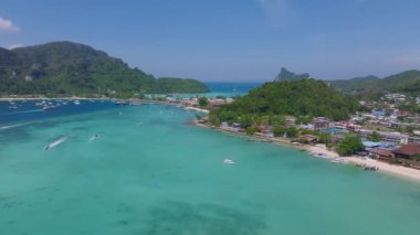 Tayland 'daki Phi Phi Adası' nın havadan görünüşü, turkuaz sular, yemyeşil tepeler, kireçtaşı kayalıklar ve hareketli bir kıyı şeridi yakınındaki tekneler..