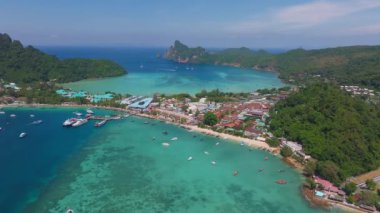 Tayland 'daki Phi Phi Adası' nın havadan görünüşü, turkuaz sular, yemyeşil tepeler, kireçtaşı kayalıklar ve çeşitli teknelerle dolu hareketli bir liman..