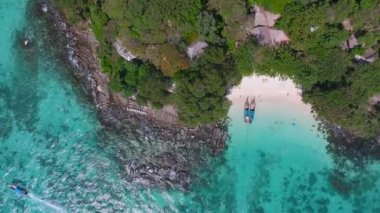 Tayland 'daki Phi Phi Adası' nın havadan görünüşü turkuaz sular, kumlu bir sahil, demirlemiş tekneler, kayalık kıyı şeridi ve yemyeşil bitki örtüsünü gösteriyor..