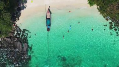 Tayland, Phi Adası 'ndaki tenha bir sahil manzarası. Beyaz kum, turkuaz su, yemyeşil ağaçlar ve geleneksel Tayland uzun kuyruklu teknesi..