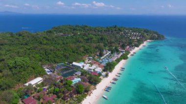 Tayland 'daki Phi Phi Adası' nın havadan görünüşü, turkuaz sular, beyaz kumlu bir sahil, renkli tekneler, yemyeşil ve kıyı tatil beldeleri.