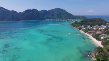 Tayland 'daki Phi Phi Adası' nın havadan görünüşü turkuvaz suları, yemyeşil uçurumlar, kumlu kıyılar ve denizde süzülen uzun kuyruklu botları gösteriyor..