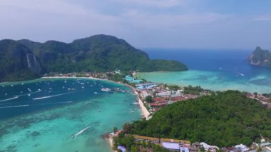 Tayland 'daki Phi Phi Adası' nın havadan görünüşü yemyeşil tepeler, kireçtaşı kayalıklar, turkuaz sular, botlar ve görünür mercan resiflerini gösteriyor..