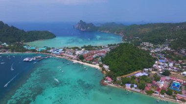 Tayland 'daki Phi Phi Adası' nın havadan görünüşü turkuaz suları, hareketli bir liman, kireçtaşı kayalıkları ve yoğun yeşil bitki örtüsü sergileniyor..