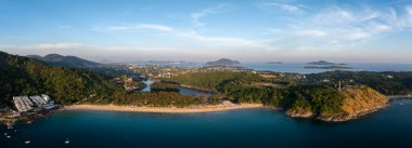 Tayland 'ın Phuket kentindeki Naiharn Sahili' nin hava manzarasında hilal, yemyeşil tepeler, lagün, beyaz binalar ve uzak adalar yer alıyor..