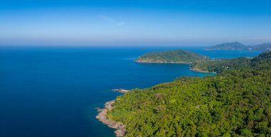 Andaman Denizi 'nin kayalık çıkıntıları, yoğun bitki örtüsü ve canlı mavi sularıyla dolu tropikal bir kıyı şeridi. Muhtemelen Phuket veya Phi Adaları' nda..