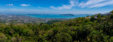 Phuket, Tayland 'ın havadan görünüşü, yemyeşil ormanlar, kentsel alanlar, turkuaz Andaman Denizi suları, uzak bir ada ve açık bir gökyüzü..