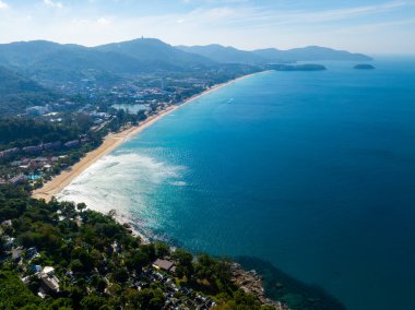 Phuket, Tayland 'ın havadan görünüşü, kumlu bir sahil, turkuaz sular, yemyeşil alanlar, tatil beldeleri, yuvarlanan tepeler ve tepedeki Büyük Buda heykeli..