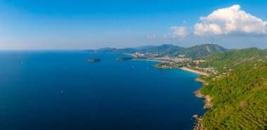 Phuket 'in kıyı şeridini gösteren tepedeki Büyük Buda heykeli, yemyeşil tepeler, kumlu sahil, mavi deniz ve dağınık küçük adalar..
