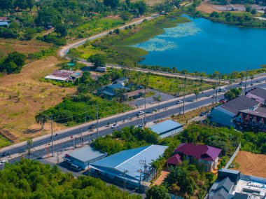 Phuket, Tayland 'daki mavi nilüfer havuzunun havadan görünüşü, yeşilliklerle çevrili yollar, trafik, konut ve ticari binalar ve açık alanlar..