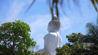 Phuket, Tayland 'daki Büyük Buda heykelinin sakin manzarası. Arkasında yemyeşil, tropikal ağaçlar ve açık mavi gökyüzü var..