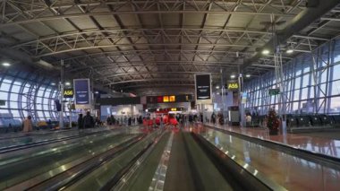 Yüksek tavanlı, cam pencereli, A5 ve A55 numaralı kapılı, dijital reklamlı ve yoğun bir günde Noel süslemeleri olan geniş bir havaalanı terminali..