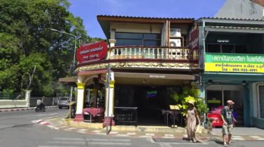 Phuket, Tayland 'daki sokak manzarasında iki katlı bir bina, Nong Catering restoranı, neon ışıklı bir buluşma noktası tabelası ve canlı yerel çevresi var..