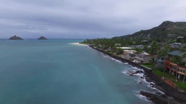 Hawaii, Oahu Adası 'nın sakin hava manzarası turkuaz suları, kumlu plajları, yerleşim yerlerini, yemyeşil evleri ve bulutlu gökyüzünün altında yuvarlanan tepeleri gösteriyor..