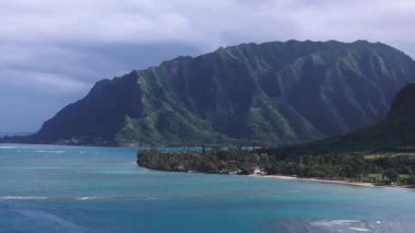 Hawaii, Oahu 'nun havadan görünüşü, yemyeşil dağları, turkuaz suları ve kumsala yakın dağınık yapıları olan el değmemiş bir kıyı şeridini gösteriyor..