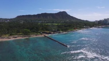 Waikiki Sahili 'nin arka planında Elmas Kafa, turkuaz sular, deniz kıyısı ve bereketli kıyı şeridi boyunca modern binalar olan yavaş bir tenceresi..