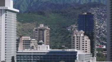 Honolulu, Hawaii 'de yavaş tava, yüksek binalar, yamaçlardaki mahalleler ve arka planda yemyeşil dağlar..