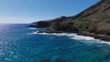 Oahu Adası 'nın kıyı şeridinin havadan görünüşü, kayalık bir dağ sırtı, kıyıya vuran okyanus dalgaları ve hareket eden araçları olan bir yol..