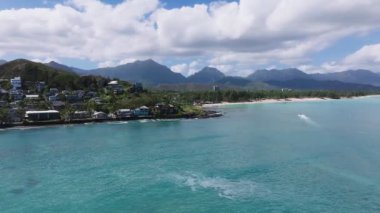 Oahu 'nun kıyı şeridinde dolambaçlı bir yol, turkuvaz suları, Ko olau dağları, yemyeşil ve uzak bir tepede mavi bir ev..