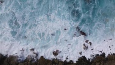 Hawaii, Oahu Adası 'ndaki engebeli kayalara çarpan dalgaların dinamik hava görüntüsü okyanus mavilerinin ve toprak renginin karşıtlığını gözler önüne seriyor..