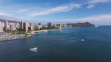 Oahu, Hawaii 'deki Waikiki Sahili' nin havadan görünüşü, Elmas Kafa, turkuaz sular, küçük tekneler, hafif dalgalar ve kentsel yüksek binalar.