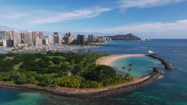 Oahu, Hawaii 'nin pürüzsüz havası, Elmas Kafa, Honolulu silueti, yeşil bir park, kayalık kıyı şeridi, turkuaz sular, ve kıyıya yakın bir yat..