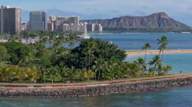 Elmas başlıklı Waikiki Sahili 'nin havadan görünüşü, turkuaz sular, palmiye kaplı kıyılar, Honolulu silueti ve okyanusta usulca hareket eden tekneler..
