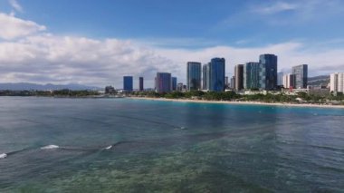 Honolulu, Hawaii 'deki Waikiki Sahili' nin havadan görünüşü turkuaz suları, mercan resifleri, yüksek binalar ve kıyı şeridi üzerinde yavaş bir tavayı gösteriyor..