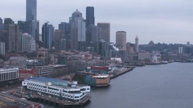 Seattle 'ın yüksek gökdelenleri, Olimpiyat Heykel Parkı' ndaki Kızıl Kartal heykeli, yeşil alanlar ve bulutlu bir gökyüzü..
