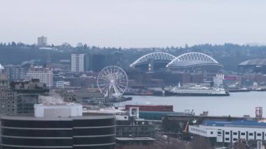 Gökdelenlerin, binaların, bulutlu gökyüzünün ve çevreleyen tepelerin ve ağaçların oluşturduğu Seattle şehir merkezinin hava manzarası..