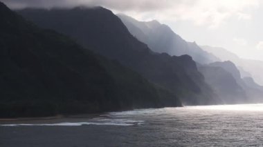 Hawaii, Kauai Adası 'ndaki Napali Sahili' nin yavaş, engebeli bir havası. Sarp kayalıklar, yemyeşil dağlar ve parıldayan okyanus suları sergileniyor..