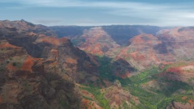Hawaii, Kauai Adası 'ndaki Waimea Kanyonu' nun havadan görünüşü. Yavaş tava kırmızı kayalıkları, yeşil bitki örtüsü ve açık mavi gökyüzü..