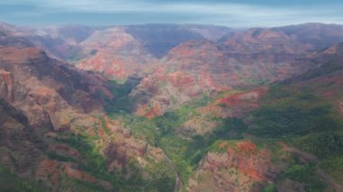 Kauai adasındaki Waimea Kanyonu 'nun havadan görünüşü, kırmızı uçurumlar, yeşil vadiler, ve yavaş, geniş drone hareketli yemyeşil bitki örtüsü..