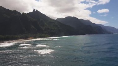 Kauai Adası 'nın kıyı şeridini süpüren, derin mavi okyanuslar, yemyeşil kayalıklar ve berrak bir gökyüzünün altındaki yoğun bitki örtüsü..