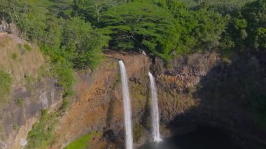 Hawaii 'deki Kauai Adası' ndaki Wailua Şelalesi 'nin havadan görüntüsü. İkiz şelaleler bir kayalık uçurumdan bir havuza akar, yemyeşil ve manzaralı bir alanla çevrilidir..