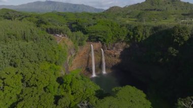 Hawaii, Kauai Adası 'ndaki Wailua Şelaleleri' nin ikiz şelaleleri, yemyeşil vadileri, tropikal bitkileri ve hareket halindeki uzak dağları gösteren hava manzarası..