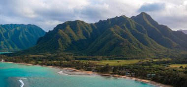 Hawaii, Oahu 'nun havadan görünüşü, keskin sırtları olan yeşil dağları, turkuaz bir kıyı şeridi, kumlu plaj, küçük yerleşim yerleri ve yoğun bitki örtüsünü gösteriyor..