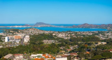 Aerial view of Oahu, Hawaii, featuring urban areas, Kaneohe Bay, Mokapu Peninsula, and the Ko olau mountain range under a clear blue sky. clipart