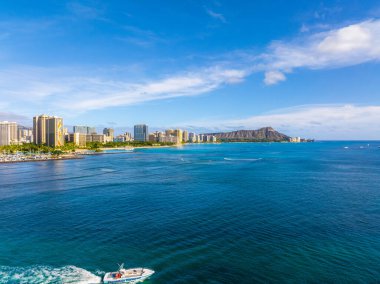 Turkuaz Pasifik suları, bir tekne, Honolulu ufuk çizgisi, ve Oahu, Hawaii 'de bulutların dağıldığı açık bir gökyüzünün altında elmas başlıklı krater..