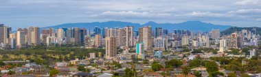 Yüksek binalar, yerleşim alanları, yeşil alanlar ve bulutlu gökyüzünün altındaki Ko olau dağ sırasının yer aldığı Honolulu, Hawaii manzarası.