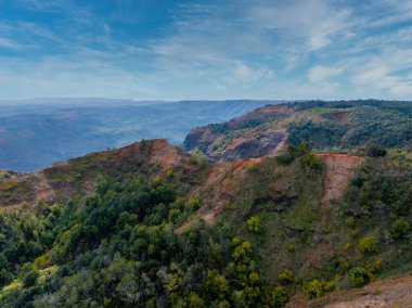 Hawaii, Kauai Adası 'ndaki Waimea Kanyonu' nun havadan görünüşü, rengarenk uçurumlar, yemyeşil bitkiler ve dağınık bulutlu parlak bir gökyüzü sergiliyor..
