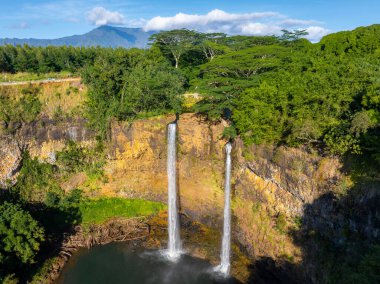 Hawaii, Kauai 'deki Wailua Şelaleleri' nde, yemyeşil yemyeşil ve uzak bir sıradağlarla çevrili sakin bir havuza şelale şelaleleri sergilenmektedir..