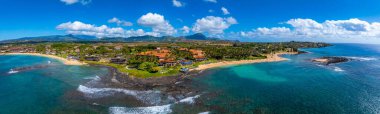 Aerial view of Kauai, Hawaii, showing golden beaches, turquoise waters, rocky outcrops, resorts with red tiled roofs, and the Napali cliffs in the background. clipart