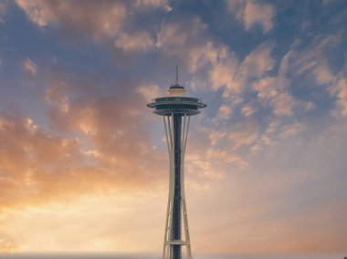 Space Needle, Seattle, Washington 'da uçan daire şeklindeki gözlem güvertesini gösteren, dağınık bulutlu, canlı bir günbatımı gökyüzüne karşı belirgin bir şekilde duruyor..