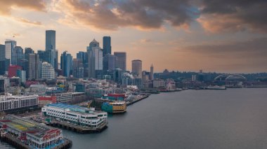 Downtown Seattles skyline features the Space Needle, skyscrapers, a cargo ship in the bay, the Seattle Great Wheel, and Lumen Field at sunset. clipart