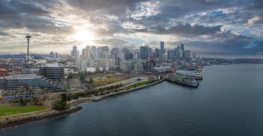 Seattle, Washington şehir merkezinin havadan görünüşü, Uzay İğnesi, modern gökdelenler, rıhtım ve dramatik bir gökyüzünün altındaki körfezde bir kargo gemisi..