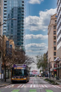 Seattle, ABD 'de canlı bir cadde, içinde bir toplu taşıma otobüsü, ikonik bir Halk Pazarı tabelası, modern ve tarihi binalar ve tramvay kabloları var..