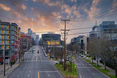 Seattle, ABD 'de sokak manzarası, şehir merkezindeki gökdelenler, renkli bir günbatımı gökyüzü, modern binalar, ve Joe Bonamassa reklam panosu.